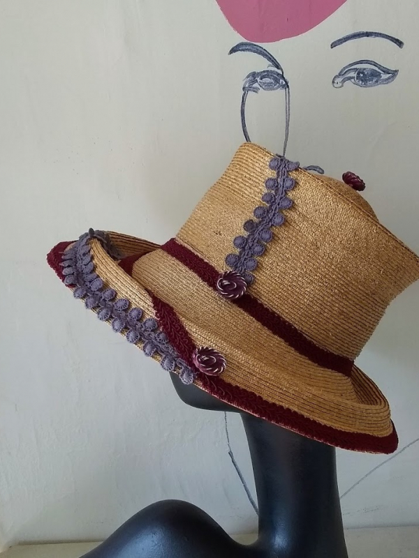 Straw hat with violet and wine colored trim.