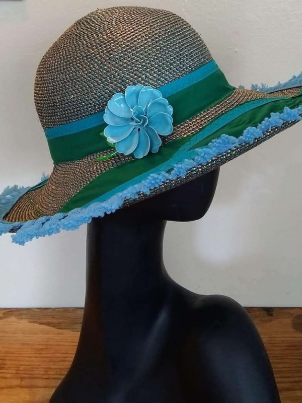 Straw hat with a blue flower and green and blue trim.