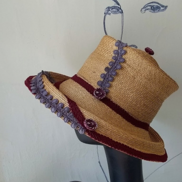 Straw hat with violet and wine colored trim.