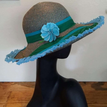 Straw hat with a blue flower and green and blue trim.